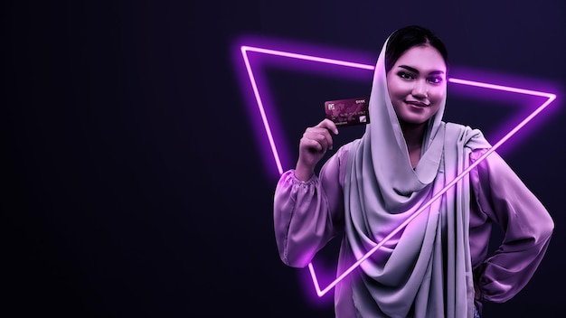 Mujer musulmana con un pañuelo en la cabeza sosteniendo una tarjeta de crédito Concepto Cyber Monday
