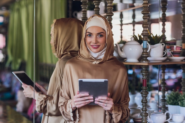 Mujer musulmana pensativa mirando tableta digital