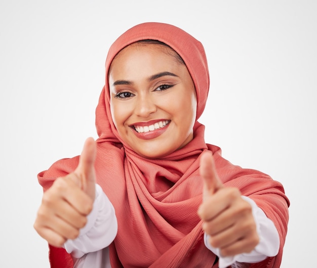 Mujer musulmana y pulgares arriba manos y acuerdo con sonrisa en retrato aislado sobre fondo blanco Opinión de hijab con apoyo de comunicación y éxito y como emoji con voto en un estudio
