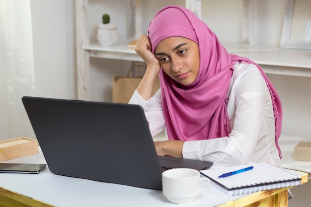 Una mujer musulmana que lleva un hijab está cansada de trabajar en la oficina. Chica árabe