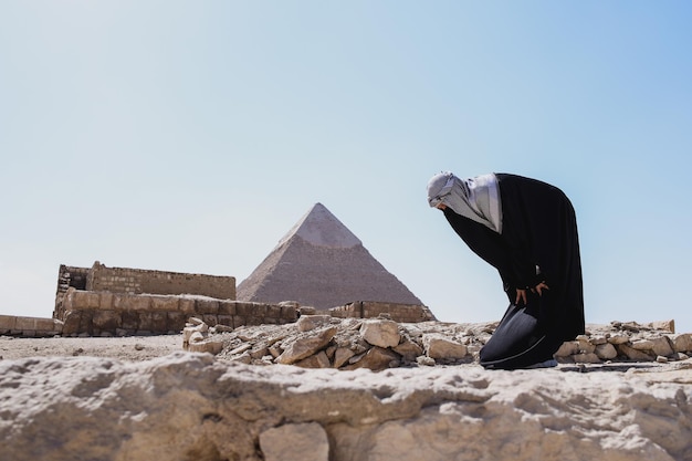 Mujer musulmana con ropa de túnica salat en pose de reverencia en el desierto