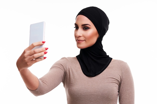 Mujer musulmana con smartphone sobre blanco