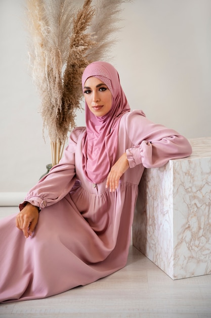 Mujer musulmana de tiro completo posando en el interior