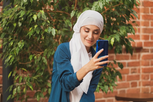 Mujer musulmana tomando selfie feliz hermosa niña con bufanda tomar una foto de sí misma usando el teléfono inteligente