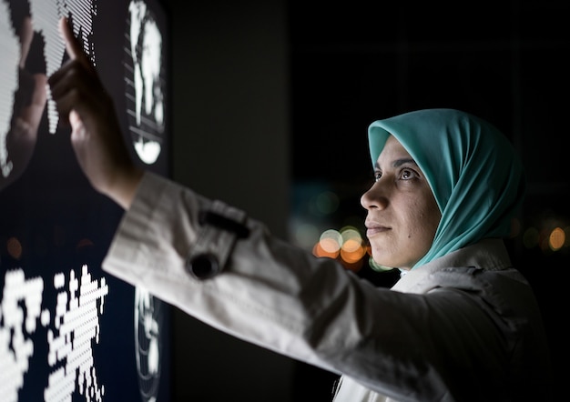 Foto mujer musulmana trabajando en pantalla de infografía inteligente