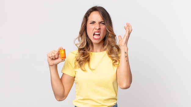 Mujer muy delgada gritando con las manos en el aire y sosteniendo las baterías