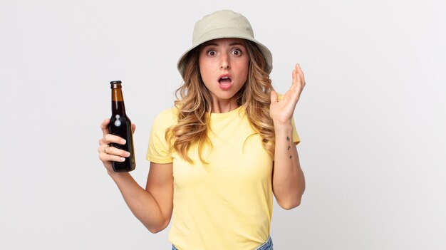 Mujer muy delgada gritando con las manos en el aire y sosteniendo una cerveza. concepto de verano