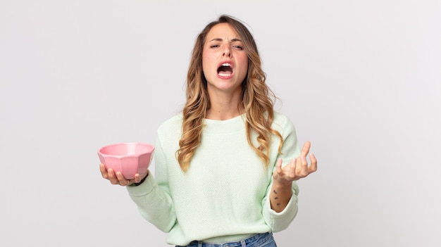 Mujer muy delgada que parece desesperada, frustrada y estresada y sosteniendo una olla vacía