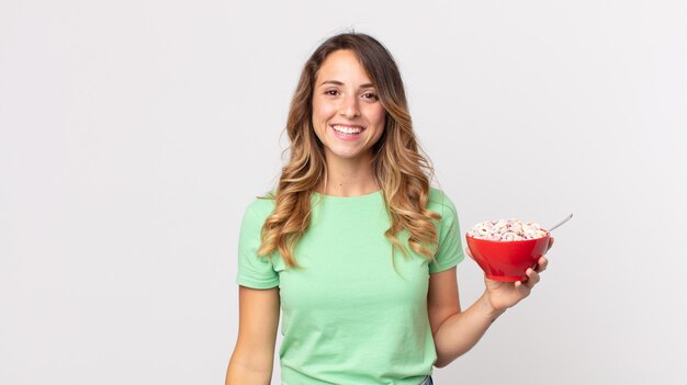 Mujer muy delgada que parece feliz y gratamente sorprendida y sosteniendo un tazón de desayuno