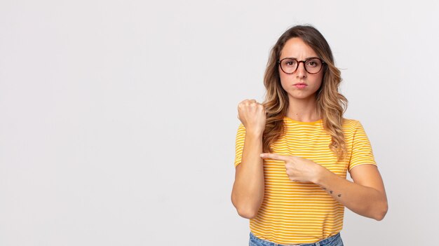 Mujer muy delgada que parece impaciente y enojada, señalando el reloj, pidiendo puntualidad, quiere llegar a tiempo