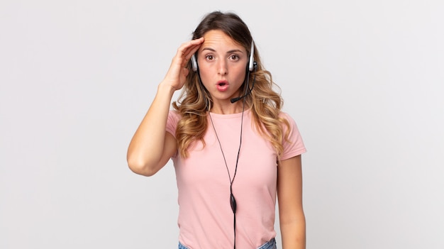 Mujer muy delgada que parece sorprendida, dándose cuenta de un nuevo pensamiento, idea o concepto. Asistente del operador con un auricular