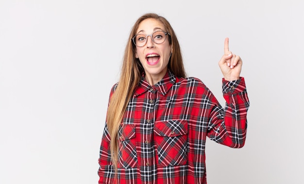 Mujer muy delgada que se siente como un genio feliz y emocionado después de realizar una idea, levantando alegremente el dedo, ¡eureka!