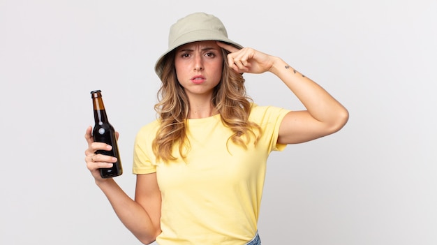 Mujer muy delgada que se siente confundida y perpleja, mostrando que estás loco y sosteniendo una cerveza. concepto de verano