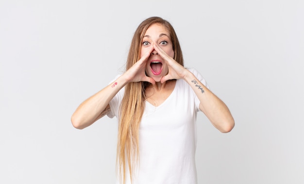 Mujer muy delgada que se siente feliz, emocionada y positiva, dando un gran grito con las manos al lado de la boca, gritando