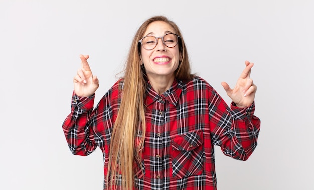 Mujer muy delgada que se siente nerviosa y esperanzada, cruzando los dedos, rezando y esperando buena suerte