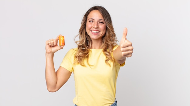 Mujer muy delgada que se siente orgullosa, sonriendo positivamente con los pulgares hacia arriba y sosteniendo las baterías