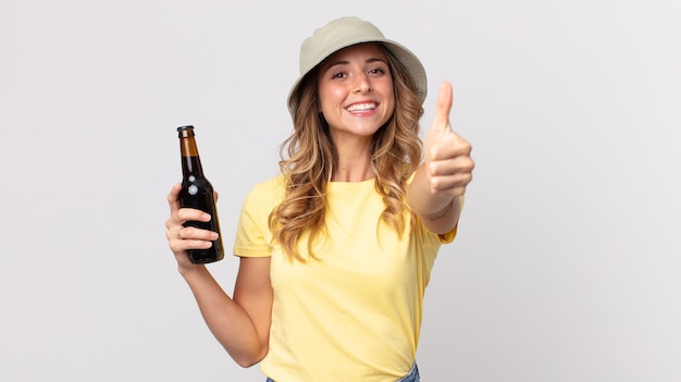 Mujer muy delgada que se siente orgullosa, sonriendo positivamente con los pulgares hacia arriba y sosteniendo una cerveza. concepto de verano