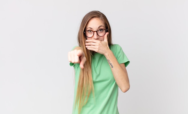 mujer muy delgada riéndose de ti, apuntando a la cámara y burlándose de ti o burlándose de ti