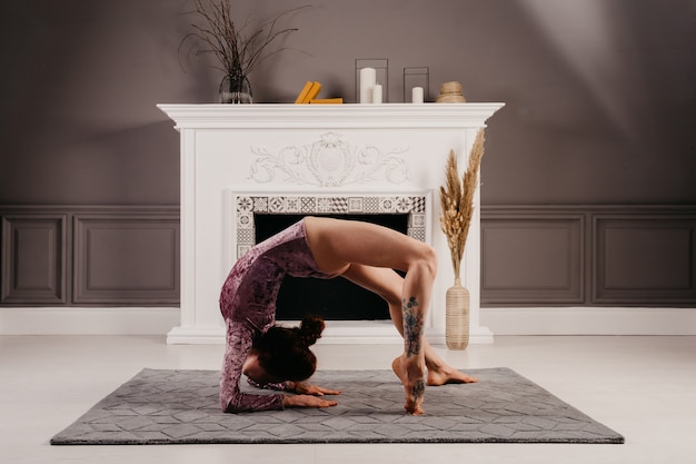 Mujer muy flexible haciendo yoga en una habitación moderna