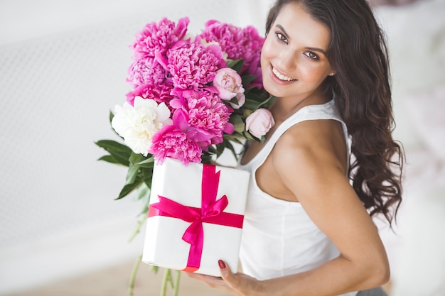 Mujer muy hermosa con peonía y caja de regalo en el interior