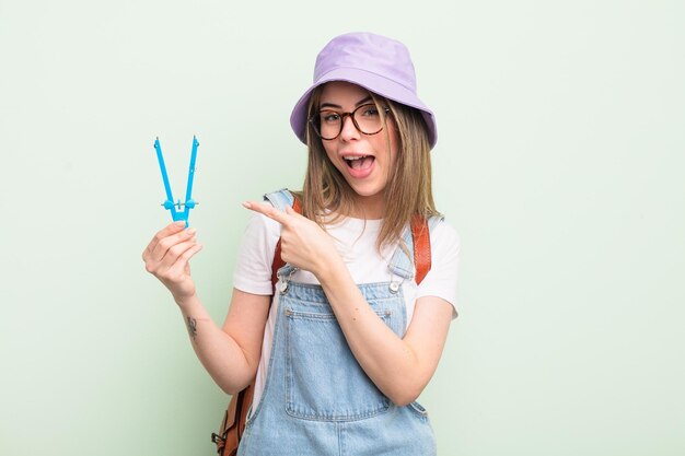 mujer muy joven que parece emocionada y sorprendida apuntando hacia un lado. concepto de estudiante