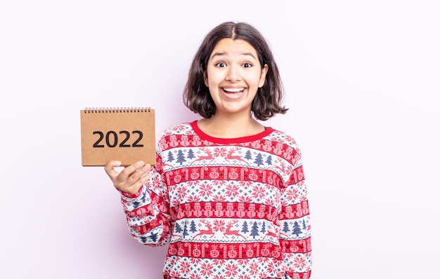 mujer muy joven que parece feliz y gratamente sorprendida. concepto de calendario 2022