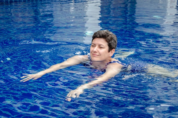 La mujer nada en la piscina La mujer practica deportes se relaja en la piscina disfruta