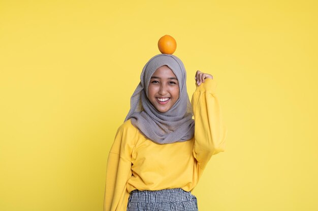 mujer con naranja sobre fondo amarillo