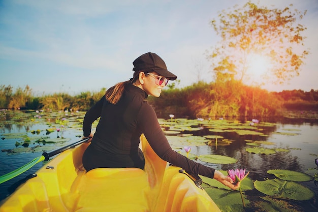 Mujer navegando en kayak de mar en la laguna de flores de loto