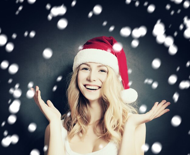 Mujer de Navidad con gorro de Papá Noel divirtiéndose sobre fondo de nieve