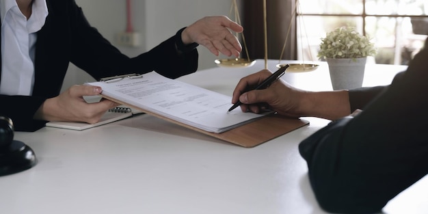 Mujer de negocios y abogados discutiendo documentos de contrato con escala de latón en escritorio de madera en la oficina Asesoramiento de servicios legales legales Concepto de justicia