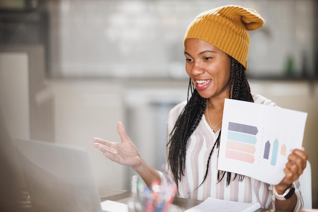 Mujer de negocios africana que usa una computadora portátil y se reúne en línea mientras trabaja desde su oficina en casa.