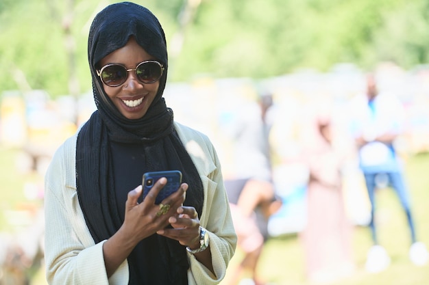 mujer de negocios africana que usa un teléfono inteligente con ropa islámica tradicional