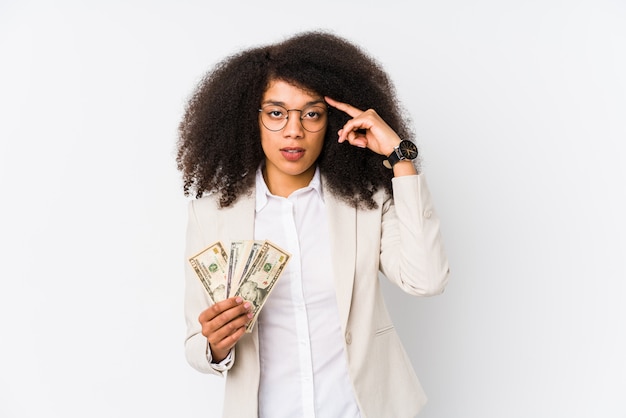 Mujer de negocios afro joven sosteniendo un coche de crédito aislado Mujer de negocios afro joven sosteniendo un templo de crédito carpointing con el dedo, pensando, centrado en una tarea.