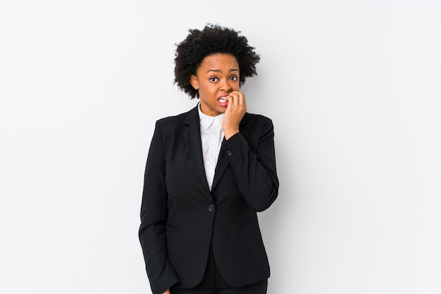 La mujer de negocios afroamericana envejecida media contra una pared blanca aisló morderse las uñas, nervioso y muy ansioso.