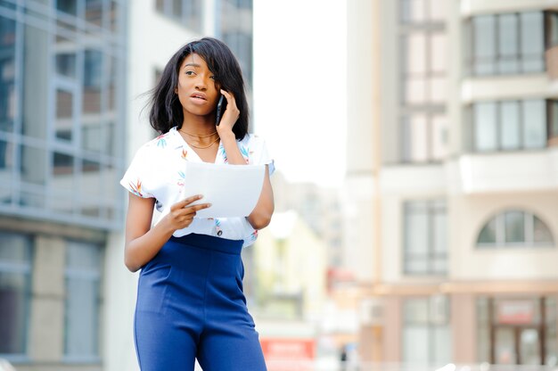 Mujer de negocios afroamericana hablando por un teléfono celular en el edificio de oficinas