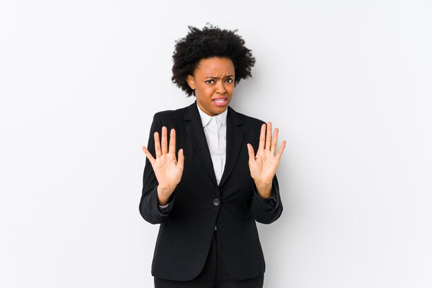 Mujer de negocios afroamericana de mediana edad contra una pared blanca aislada rechazando a alguien que muestra un gesto de asco.