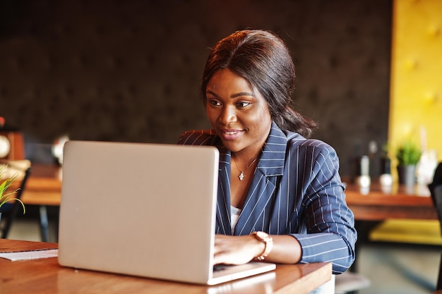 Mujer de negocios afroamericana sentada en la mesa en el café Chica negra trabajando con una computadora portátil