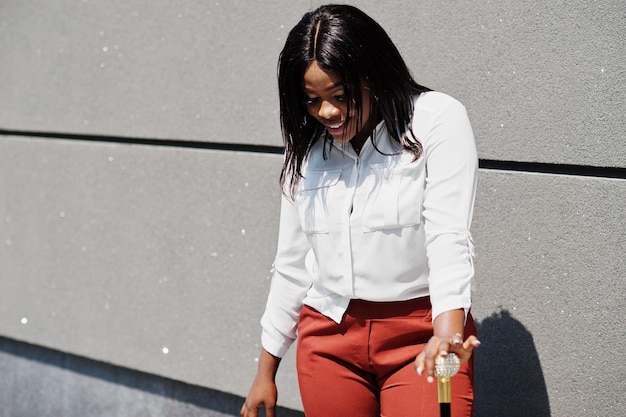 Mujer de negocios afroamericana vestida formalmente con blusa blanca y pantalón rojo con bastón en la mano Exitosa mujer de negocios de piel oscura