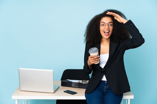 Mujer de negocios afroamericano que trabaja en su lugar de trabajo con expresión de sorpresa