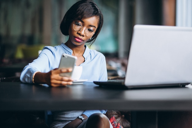 Mujer de negocios afroamericano con teléfono y computadora portátil