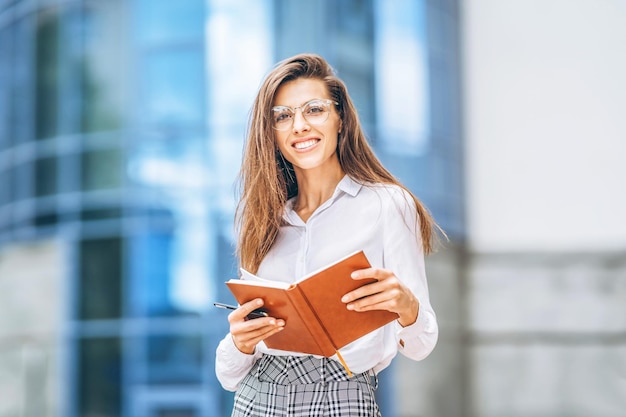 Mujer de negocios al aire libre cerca del moderno centro de negocios con portátil