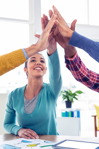 Mujer de negocios alegre que hace el alto cinco con el equipo en oficina creativa