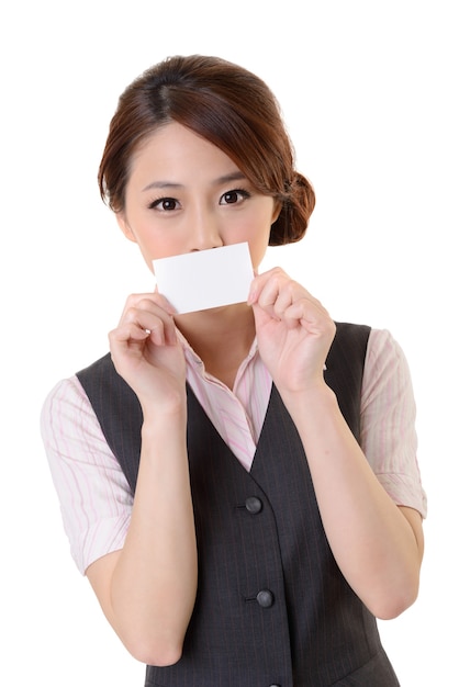 Mujer de negocios alegre que sostiene la tarjeta de visita en blanco, retrato del primer en la pared blanca.