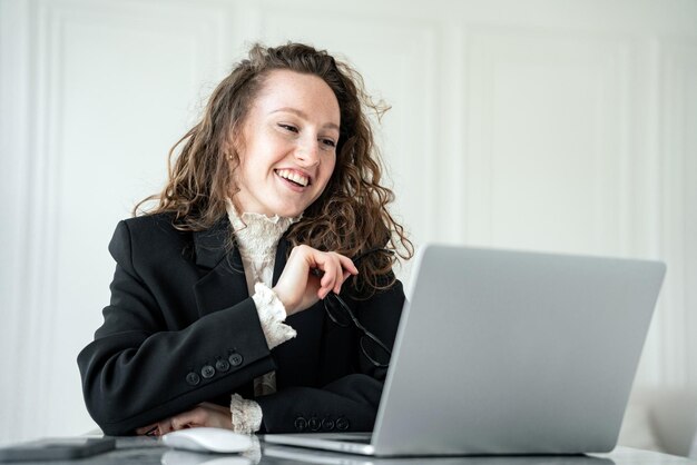 Mujer de negocios alegre riendo durante una videollamada en su computadora portátil disfrutando de un momento alegre