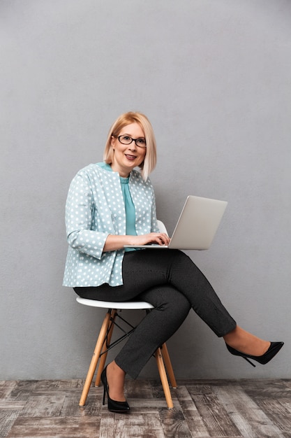 Mujer de negocios alegre usando la computadora portátil.