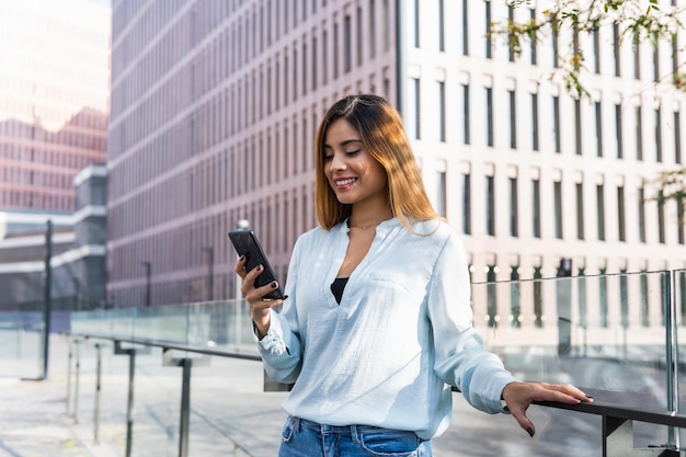 Mujer de negocios alegre usando el teléfono móvil al aire libre