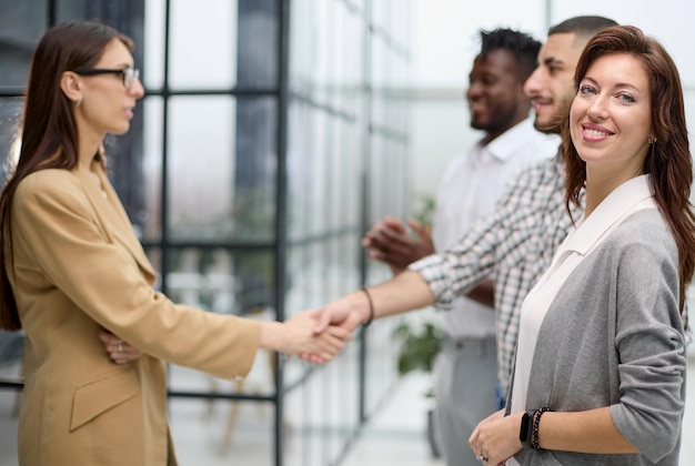 Mujer de negocios ambiciosa sonriendo a la cámara en el contexto de una reunión de colegas