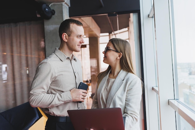 Mujer de negocios apuntando con el dedo a una computadora portátil para un colega masculino Cooperación comercial y trabajo en equipo Millennials europeos en la mesa de la oficina Gente exitosa moderna