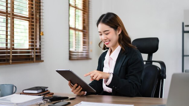 Mujer de negocios apuntando a la tableta para leer datos financieros y plan de marketing de un nuevo proyecto de inicio